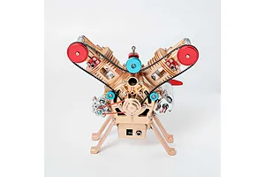 A front view of the Teching M114 V2 engine model kit, featuring a gold-colored metal frame, red pulleys, and blue accents against a white background.
