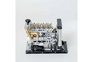 A detailed 1/10 scale metal model of a 4-cylinder diesel engine by Teching, featuring silver and gold components on a black base.
