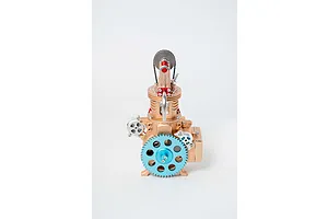 Front view of a Teching DM117 single cylinder engine model kit featuring a large light blue gear and gold-toned metal components.