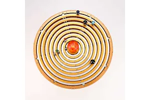 Top-down view of a Teching DM405 solar system metal model kit featuring concentric golden gear rings and colorful planet spheres around a central sun.