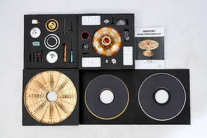 Top-down view of the Teching DM405 Solar System model kit components laid out in foam trays with an instruction manual.