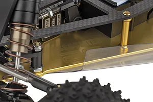 Close-up of the gold-anodized aluminum chassis of a Team Associated RC10 buggy, showing carbon fiber components and suspension details.