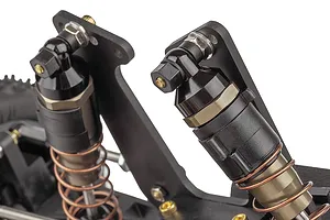 Close-up of the front suspension and shock absorbers on a Team Associated RC10 RC buggy, showing black shock bodies and copper-coloured springs.