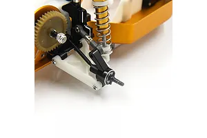 A close-up view of a black aluminium rear hub installed on an RC car chassis, featuring white suspension arms and a gold shock absorber.