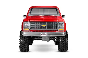 Front view of a red Traxxas TRX-4 1979 Chevrolet Cheyenne K10 RC rock crawler on a white background.