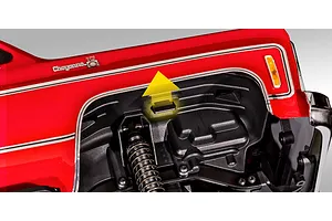 Close-up of the Traxxas TRX-4 Chevrolet K10 wheel well showing the body mounting clip location with a yellow arrow indicator.