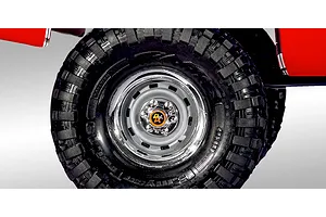Close-up of a Traxxas TRX-4 RC crawler wheel featuring a chrome steel-style rim with a 4x4 center cap and aggressive tread pattern.