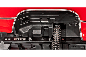 Close-up of the wheel well and suspension area of a Traxxas TRX-4 RC crawler, showing the inner fender, coil-over shock, and chassis rail.