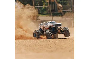 An ARRMA Freedom Flyer RC monster truck kicking up a large cloud of dust while driving on a dirt track.