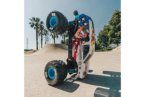 ARRMA Freedom Flyer Grom RC monster truck performing a wheelie on a concrete skate park surface under a clear blue sky.