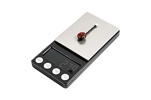 A single BetaFPV 1102 brushless motor with red and black casing sitting on a digital scale showing a weight reading.