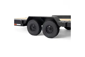 Close-up side view of the dual-axle wheels and black plastic fenders on an Axial 1/10 scale flatbed RC trailer.