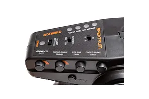 Close-up of the top control panel on a Spektrum DX3 RC transmitter showing adjustment knobs, switches, and labels.