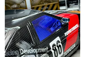 A close-up view of an RC car body featuring a blue tinted window sticker applied to the side window.