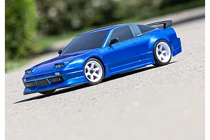 A blue Traxxas Nissan 240SX RC drift car on a paved surface with white wheels and a rear spoiler.
