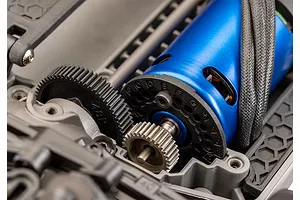 Close-up of a blue electric RC motor and black plastic spur gear mounted on a grey composite chassis.