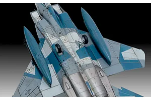 A high-angle view of the underside of a painted and weathered F-15C Eagle model aircraft, showing landing gear, fuel tanks, and blue-grey camouflage.
