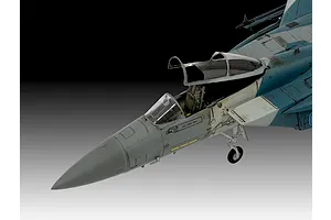 Close-up of a 1/72 scale plastic model F-15C Eagle fighter jet, showing the cockpit area, nose, and landing gear against a gradient background.