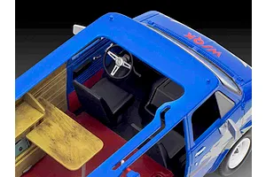 High-angle view of the interior of a blue Revell Stranger Things Squawk Van model kit showing the driver seat, steering wheel, and wooden work desk.