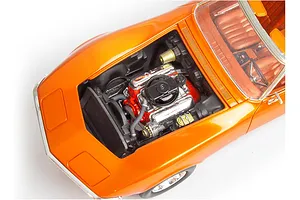 High-angle close-up of a 1/25 scale orange model Corvette with the hood open, showing the detailed engine bay.