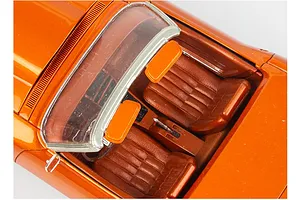 Top-down view of the interior of a metallic orange scale model Corvette showing bucket seats, center console, and windshield frame.