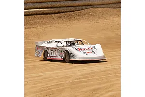 A white Losi 22S Dirt Late Model RC car with Summit Racing livery racing on a dirt oval track.