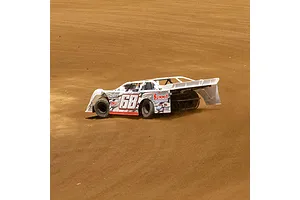 A white Losi 22S Dirt Late Model RC car with number 68 racing on a dirt track.