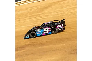 A Losi 22S Dirt Late Model RC car racing on a dirt track, featuring a black, blue, and pink livery with the number 5K on the side.