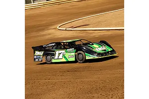 A green and black Losi 22S Dirt Late Model RC car racing on a dirt track.