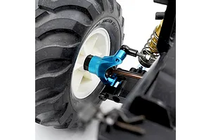 Close-up of a blue anodized aluminium RC car steering hub installed on a vehicle with a black rubber tyre and white wheel rim.