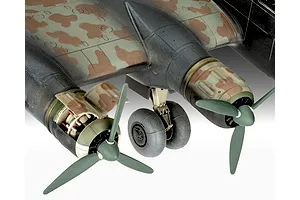 Close-up of a scale model aircraft wing showing two engines, propellers, and landing gear with camouflage paint.