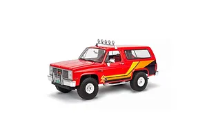A 1/25 scale model of a red 1985 GMC Jimmy High Roller SUV with yellow and black side decals and a roof-mounted light bar.