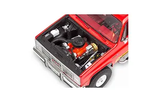 High-angle view of the detailed engine bay of a red 1/25 scale Revell 1985 GMC Jimmy model kit with the hood open.