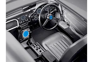 Close-up interior view of a 1/24 scale Aston Martin DB5 model kit showing the dashboard, steering wheel, and driver seat.