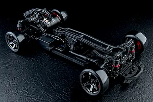 A high-angle studio shot of the MST RMX 4.0 RC drift car chassis, showing the brushless motor, suspension, and wheels on a black textured background.