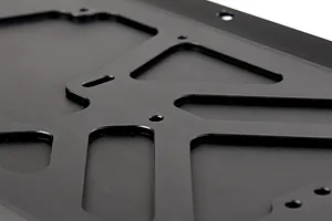 Close-up of a black anodized aluminium RC main chassis plate with machined cutouts and mounting holes.