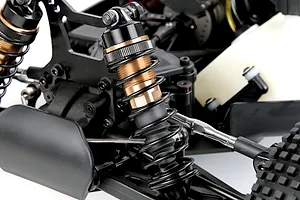 Close-up of bronze and black adjustable RC shock absorbers installed on a remote control vehicle chassis.