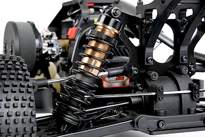 Close-up of a bronze and black adjustable shock absorber installed on the rear suspension of an RC buggy.