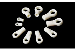 A set of white plastic ball ends of varying sizes arranged in a circle on a black background.