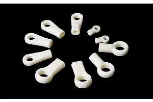 A collection of white plastic RC ball ends of various sizes arranged in a circle against a black background.