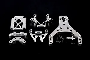A set of silver aluminium RC front bulkhead components and an upper plate with mounting hardware on a black background.