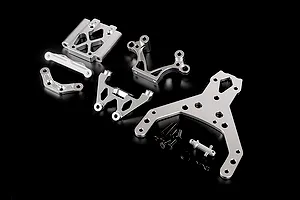 A set of silver aluminium RC car front bulkhead components and an upper plate laid out on a black background.