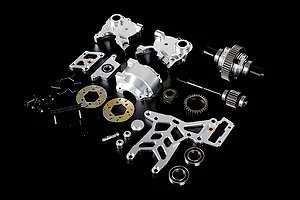 A collection of silver aluminium RC car differential and transmission parts laid out on a black surface.