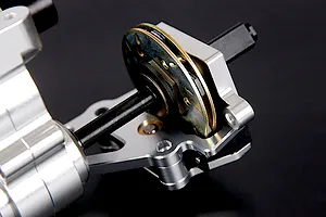 Close-up of a silver aluminium RC car transmission assembly with a brake disc mechanism on a black background.