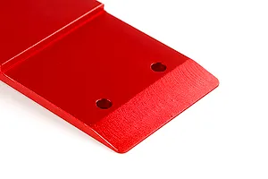 A close-up view of a red anodized aluminium front skid plate for an RC car, showing the angled edge and mounting holes.