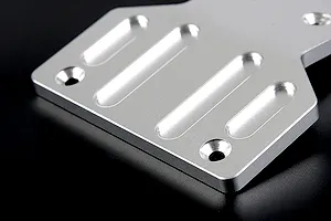A close-up view of a silver aluminium front skid plate for an RC vehicle, featuring machined slots and countersunk screw holes.