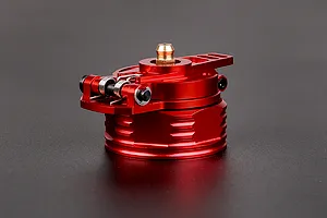 A red anodized aluminium RC fuel tank cap with a spring-loaded hinge and brass breather nipple, set against a dark grey background.