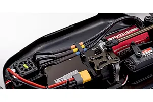 Close-up of the internal electronics layout of the Kyosho Inferno MP10e electric RC buggy showing the motor, ESC, and wiring.
