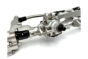 Close-up studio shot of a silver aluminium RC front portal axle set showing detailed metal machining, hardware, and steering linkages.
