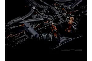 Close-up studio shot of the RC Maker SP2 touring car chassis featuring carbon fibre and bronze coloured alloy components.